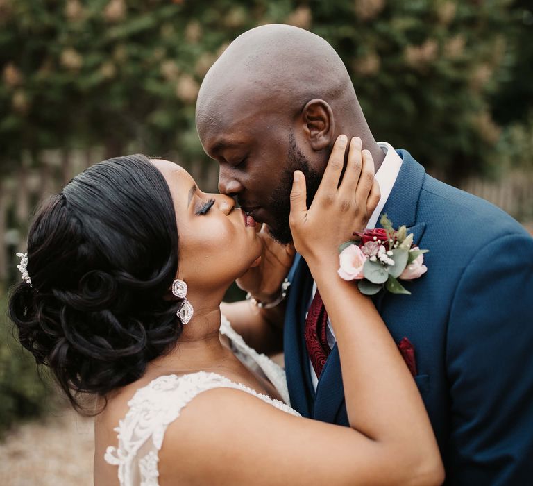 A bride wears a low bun as an example of great hairstyles for Black brides. She kisses her new husband.