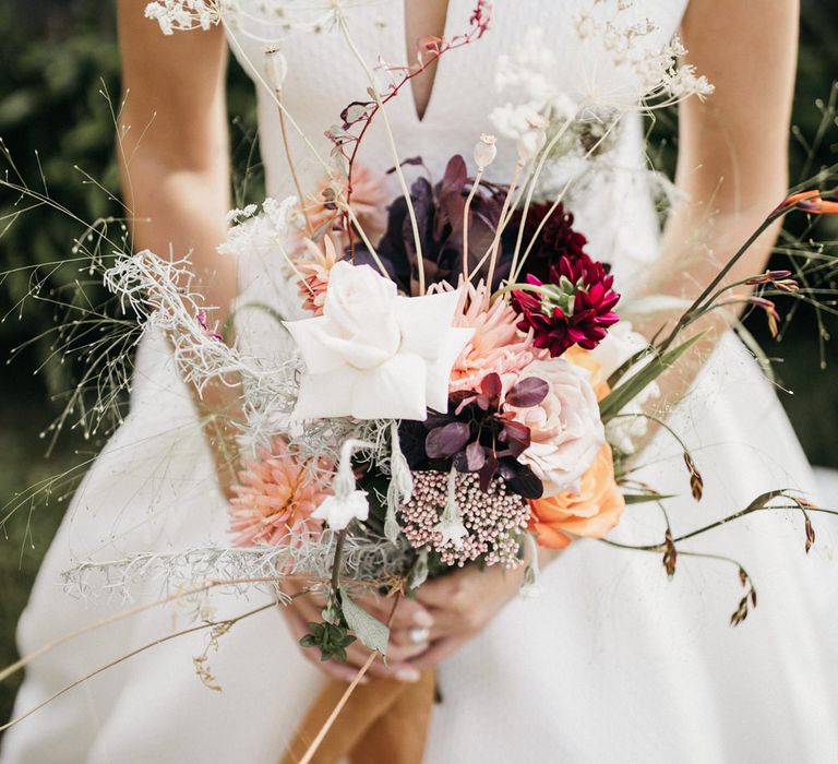 Bride holding an unstructured wildflower wedding bouquet 