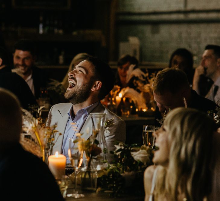 Groom and guests seated and laughing at speeches