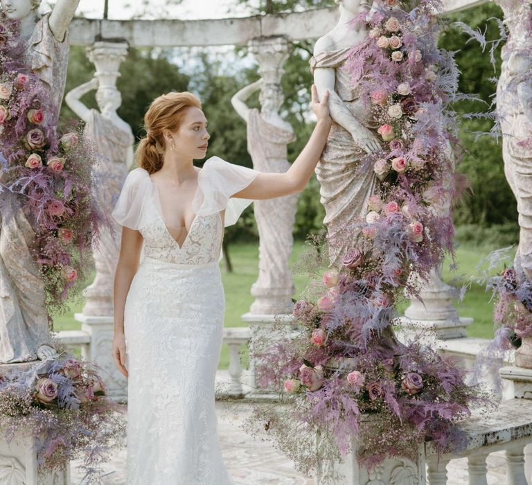 Bride poses in front of bandstand surrounded by lilac flowers