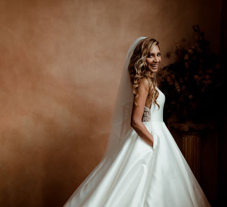 Beautiful bride with side swept wavy hair in a Justin Alexander wedding dress with pockets. 