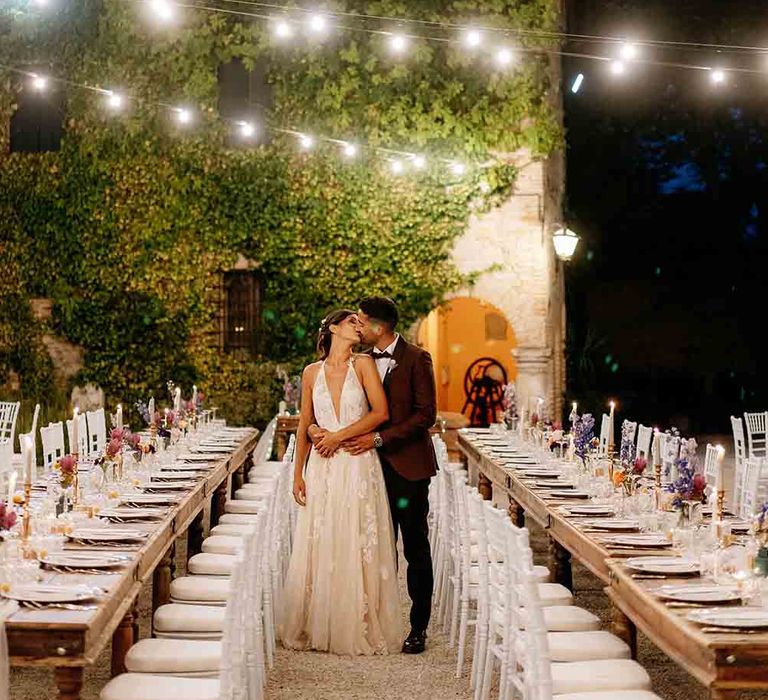 Festoon lighting hangs over long tables for wedding