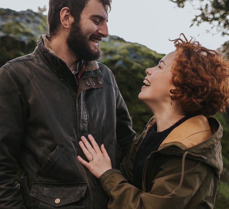 Couple laugh together outdoors during engagement session