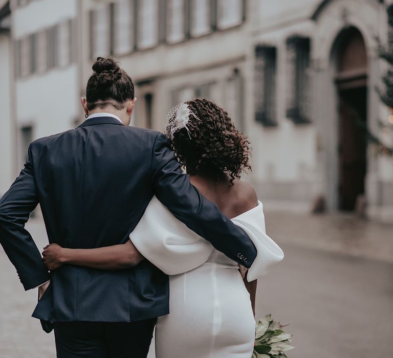 Bride & groom walk together with their arms around one another