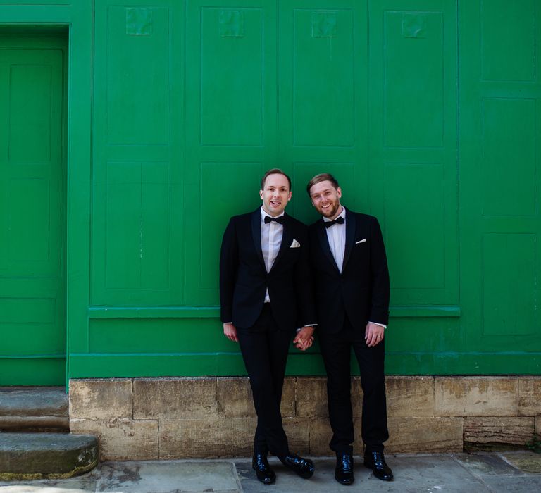 Groom stand in front of green wall outside in Oxford