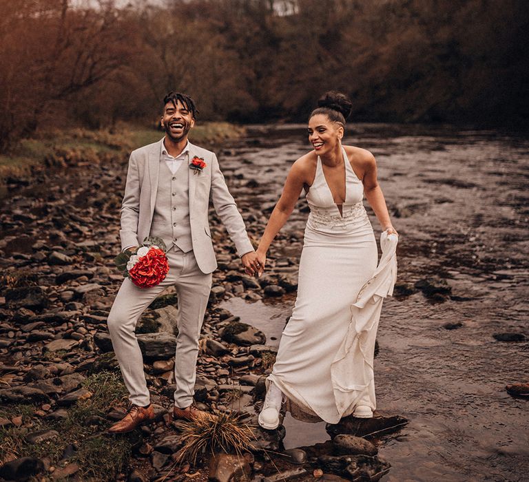 Bride & groom walk together outdoors as they hold hands and bride wears wedding Dr Martens