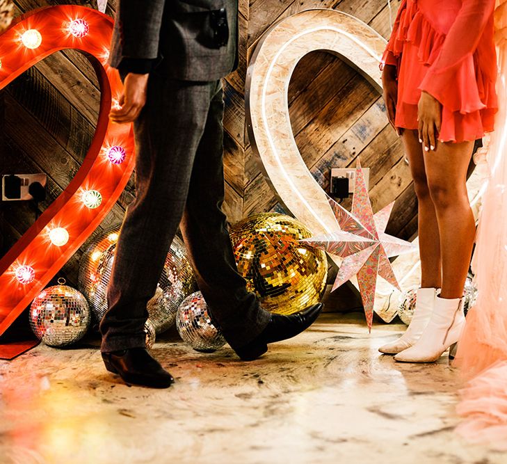 Bride in white boots with neon wedding signs and disco balls on the floor 