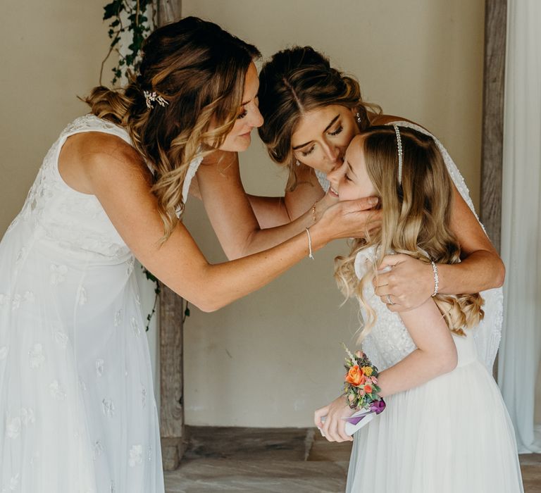 Brides kiss & hug daughter during wedding ceremony 