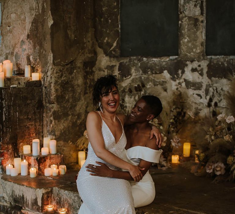 Bride in a sparkly wedding dress with thin straps sitting on her brides lap in a strapless wedding dress