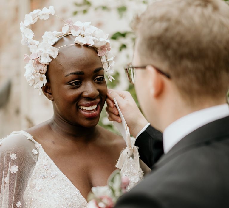 A Black bride with alopecia smiles at her husband as they exchange vows.