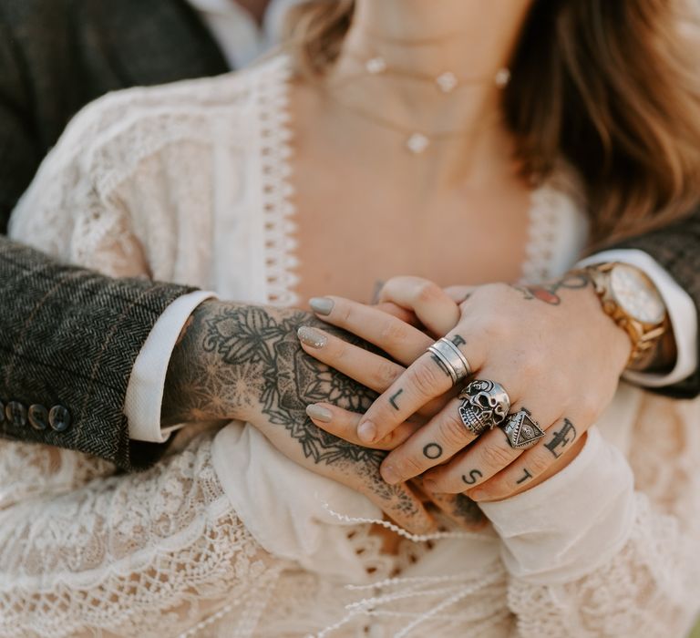 Tattooed groom holds hands with his bride