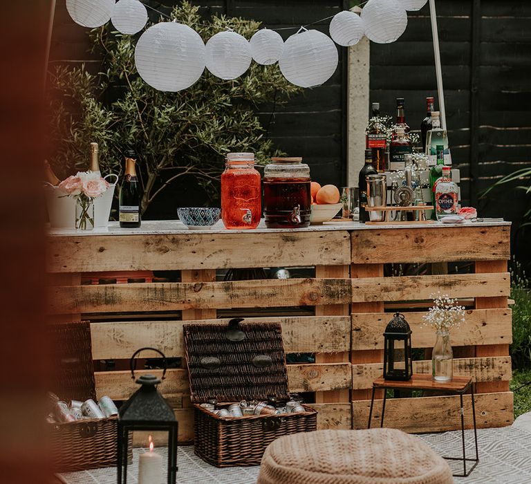 DIY wooden palette drinks station with drinks dispensers, baskets of beer and paper lantern bunting 