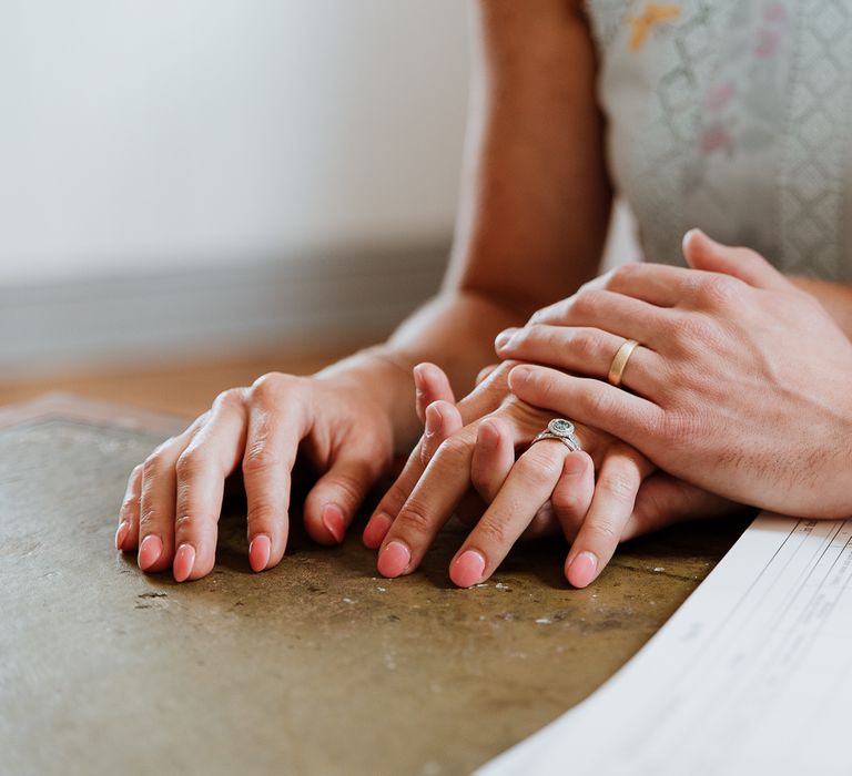 Bride & groom hold hands with one another and brides nails are painted in a pale pink