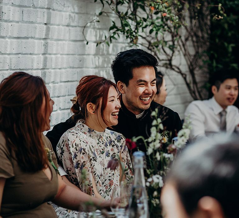 East Asian bride and groom smiling during the wedding speeches at Carousel in Marylebone