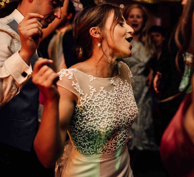 Bride in white Rime Arodaky wedding dress with lace top dances with groom and wedding guests during evening wedding reception in Dorset