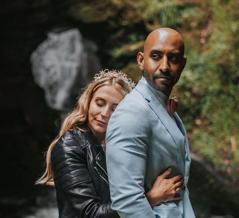 Bride holds her groom from behind as she wears personalised leather jacket