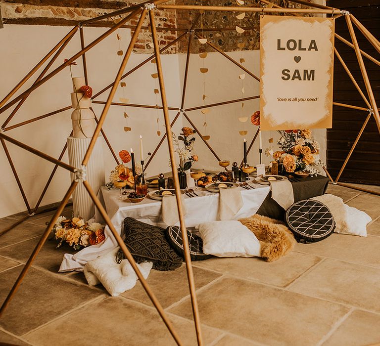 Grazing table with cushions under a wooden geodome frame 