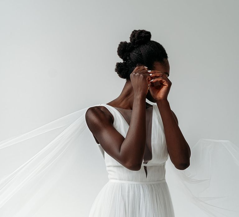 Black bride in a pleated wedding dress with plunging neckline wearing a Watteau cape