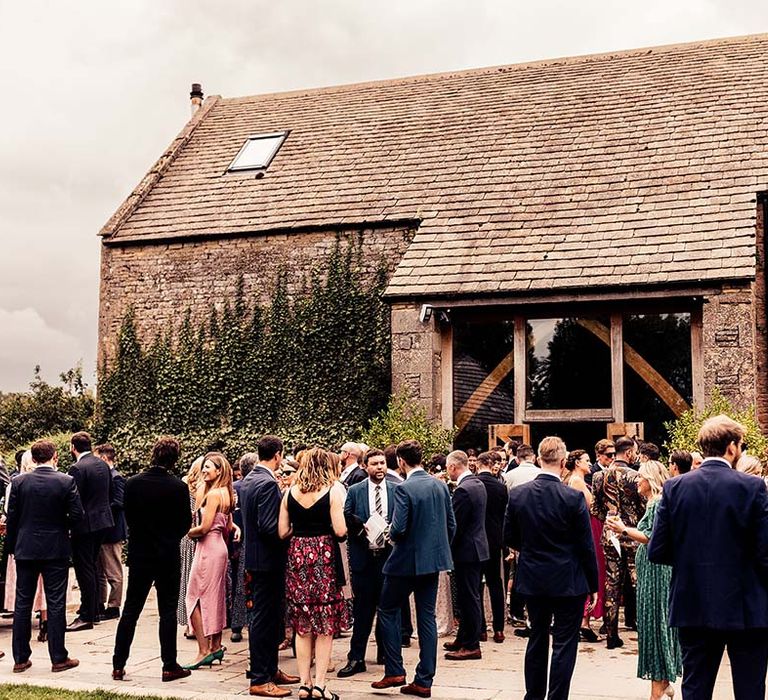 Wedding guests gather outside the Stone Barn Cotswolds for rustic wedding