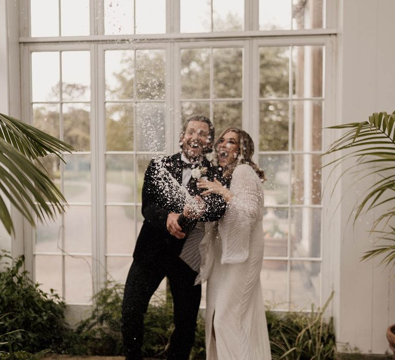 Bride and groom popping champagne at black tie wedding at Tatton Park 