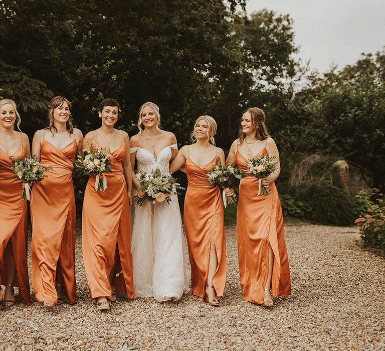 Bridesmaids in orange wrap dresses for summer wedding