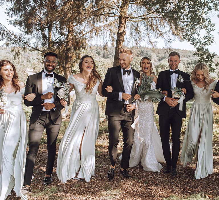 Bride & groom stand with their wedding party outdoors