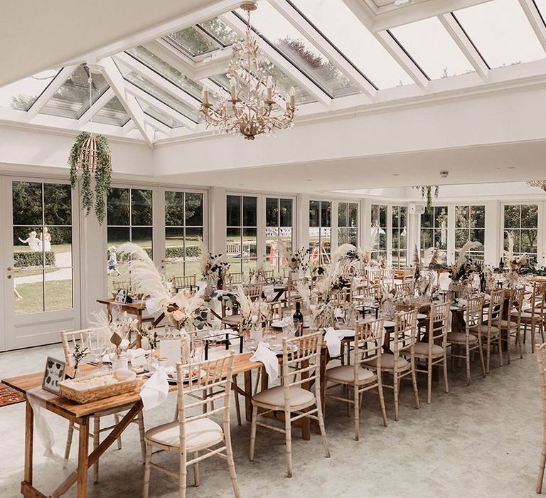 Wedding reception complete with white chairs and open vibe with dried floral arrangements