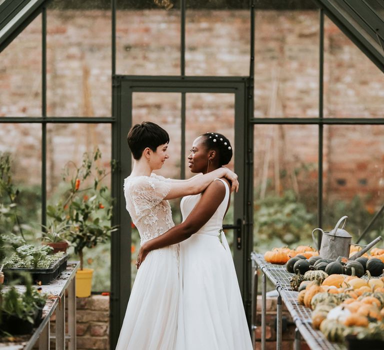 Autumn wedding with a bride with short hair in a romantic wedding dress embracing her Black bride in a minimalist wedding dress 