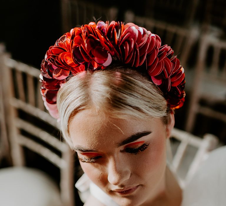 Bride with orange eyeshadow and long eyelashes wearing a red applique headdress 