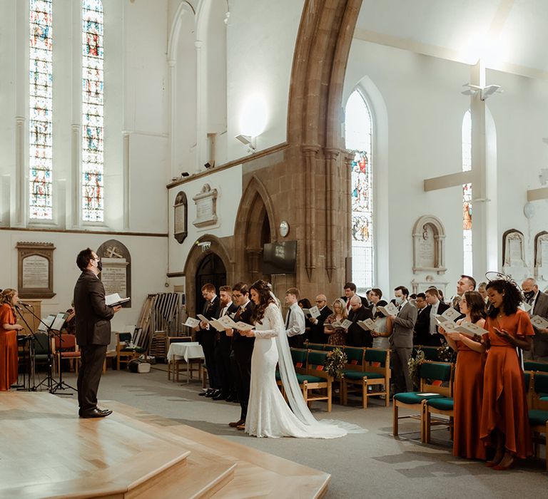 Bride and groom and wedding guests standard sing hymns for the church wedding ceremony