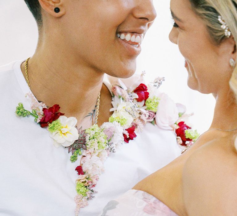 Intimate couples portrait with bride in a strapless flower wedding dress and groom in a white t-shirt and flower collar 