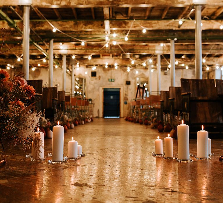 Aisle style with candles and warm toned flowers for industrial wedding venue