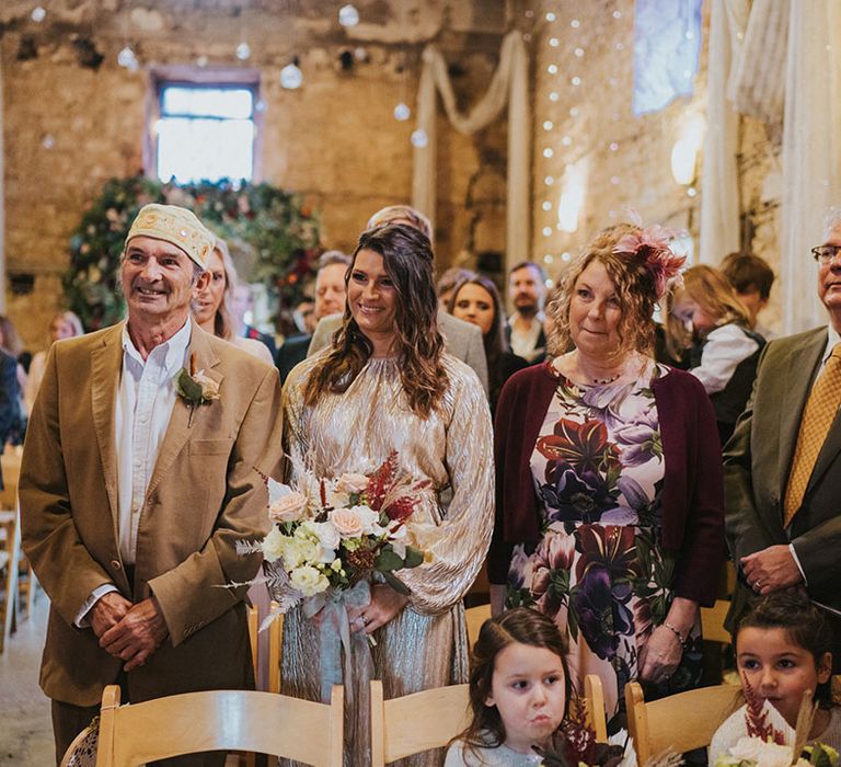 Wedding guests stand for the wedding with flower girls in grey dresses with cardigans