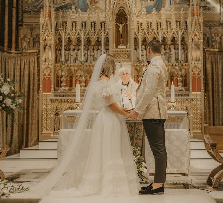 Bride and groom stand at the altar of Farm Street Church for their city wedding