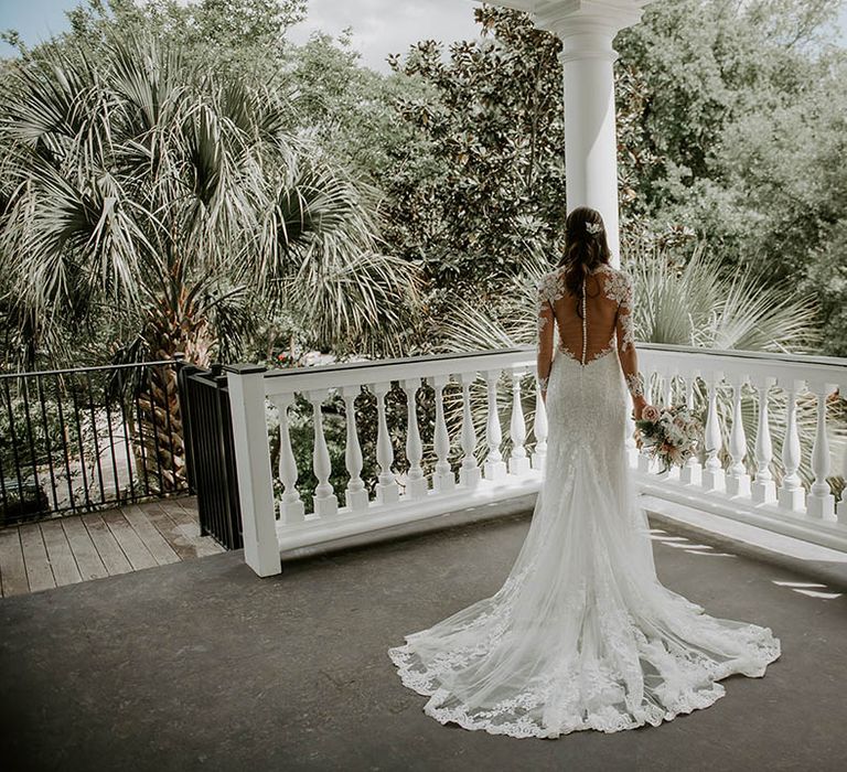 Bride in long sleeve illusion lace wedding dress with long sleeves and button detail with a train 