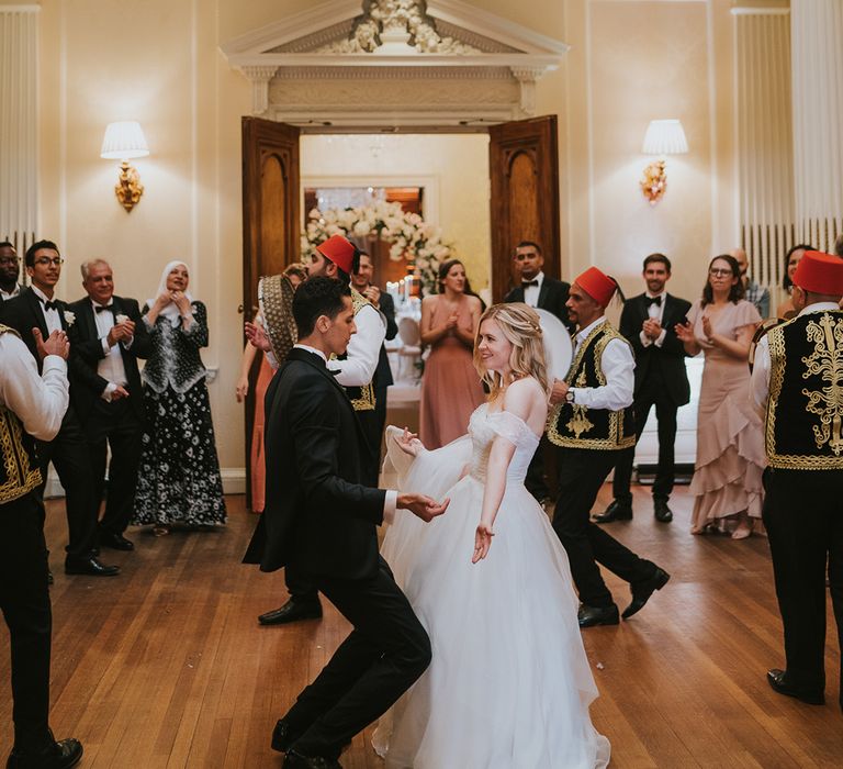 Bride and groom dance for their classic wedding with Zaffa band playing around them 