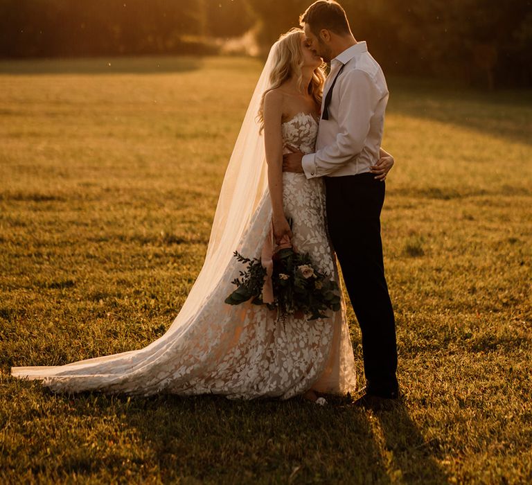 Bride and groom share a kiss as golden hour hits for beautiful couple portrait 