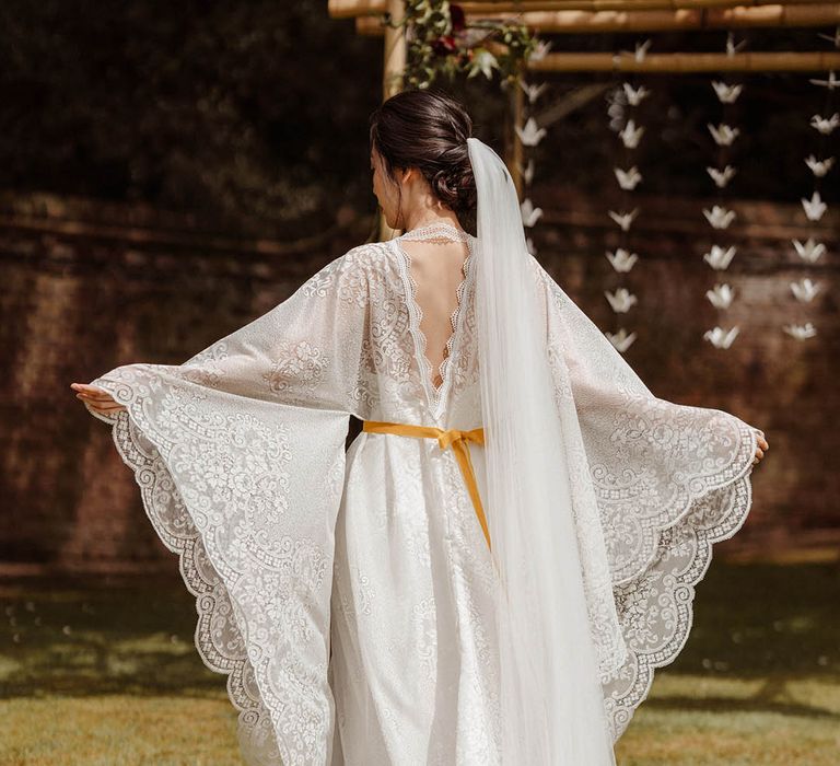 East Asian bride in a lace Kimono-style wedding dress with long sleeves and yellow dipped long veil