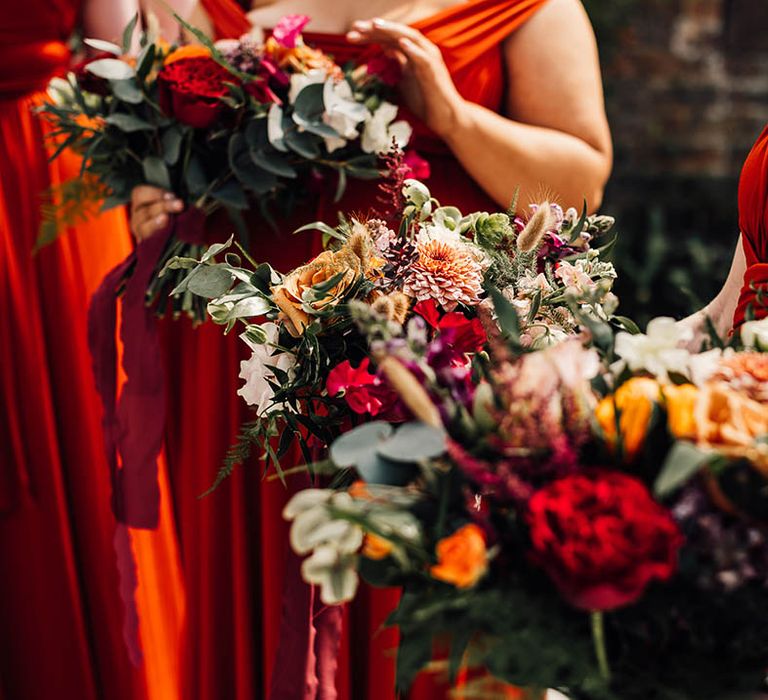 Warm toned orange and red bouquets for the bridesmaids 