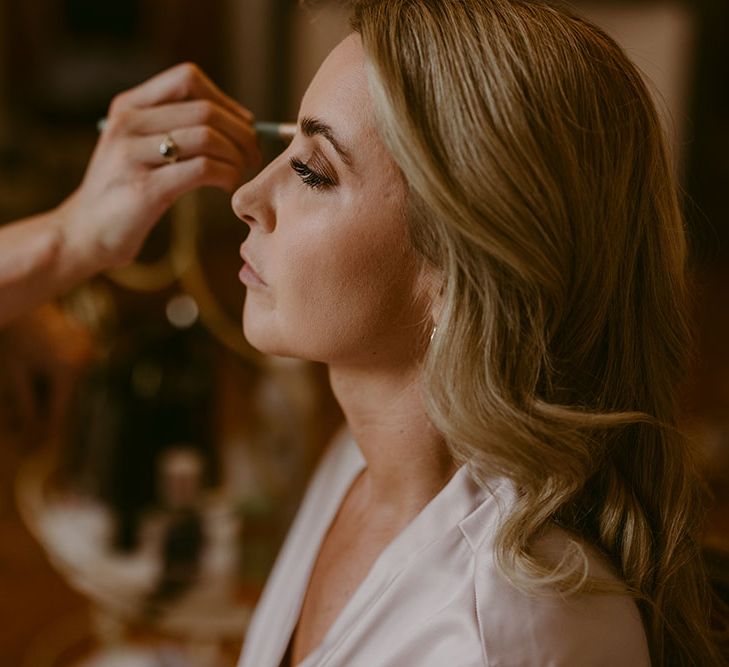 Blonde bride has her makeup done on the morning of her wedding day