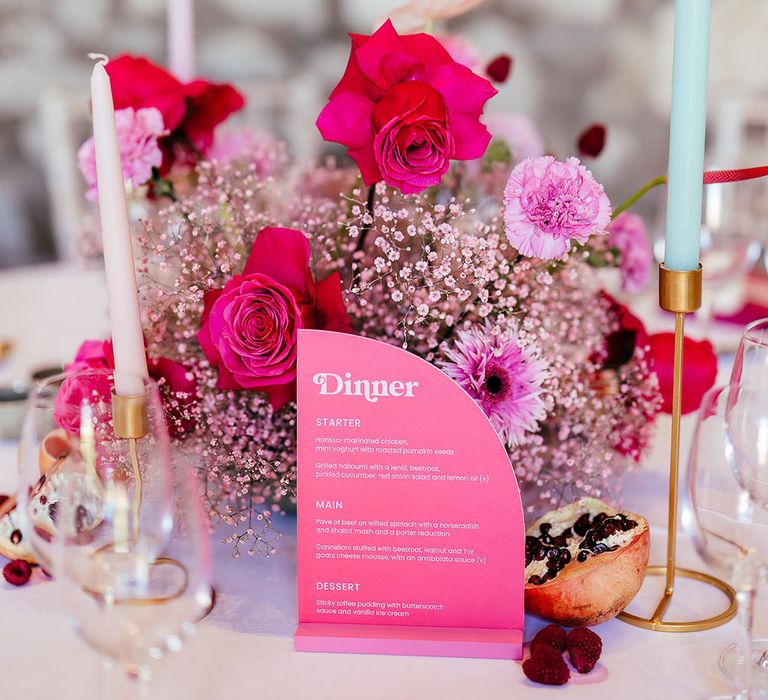 Bright pink floral centrepiece for modern tablescape complete with pastel coloured candles and dried fruit decor 