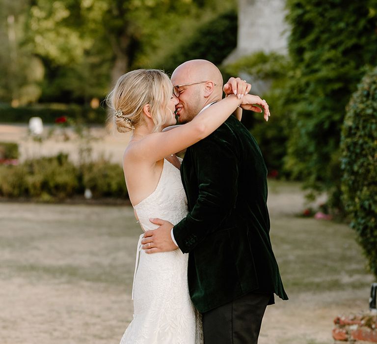 Bride & groom kiss outdoors at Bisham Abbey during summer wedding with Krispy Kreme doughnut tower