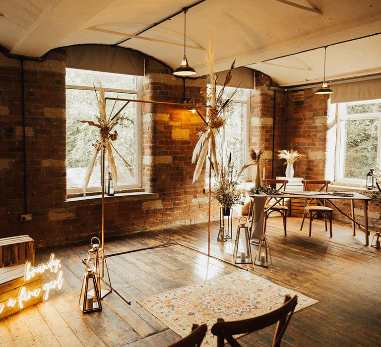 Rustic styled ceremony room complete with brass arch with pampas grass installations and neon wedding signage 