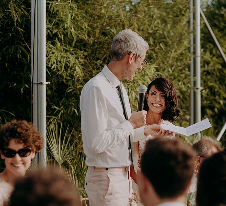 Groom looking at a smiling Bride while he reads his wedding speech