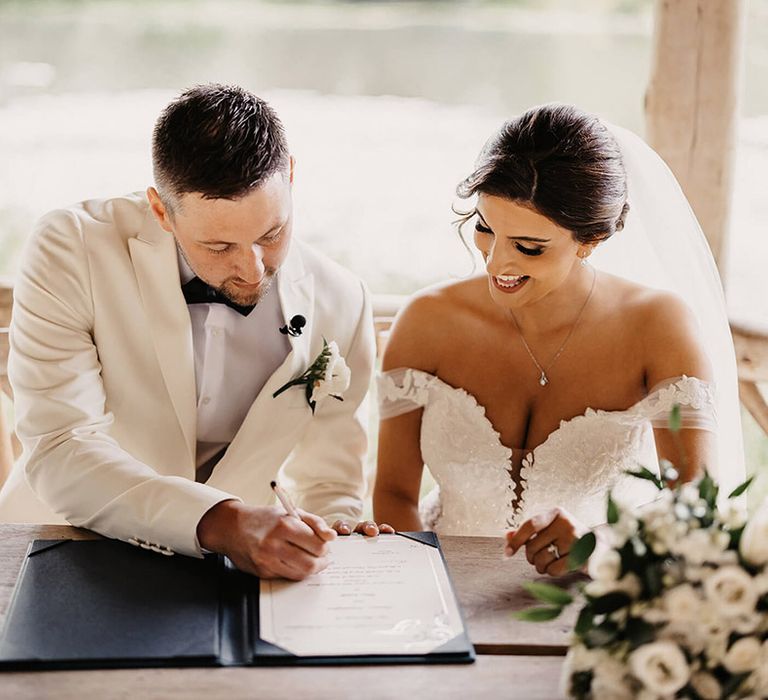 The bride and groom sign their wedding register after their outdoor ceremony 