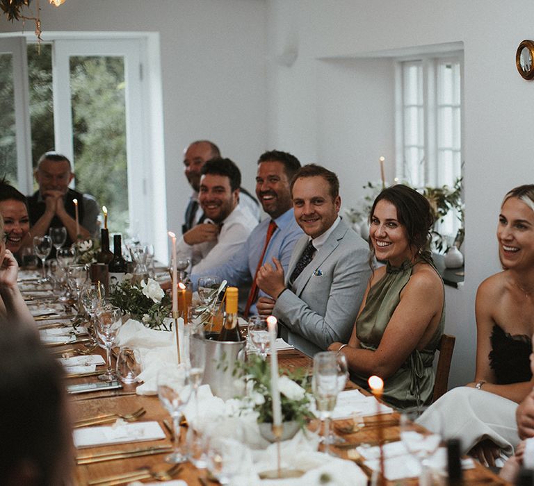 Wedding guests laugh during speeches at intimate wedding reception 