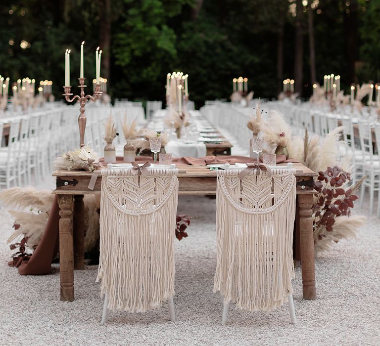 Macrame chair decor complete with wooden banquet tables and neutral toned decor for Italian destination wedding 