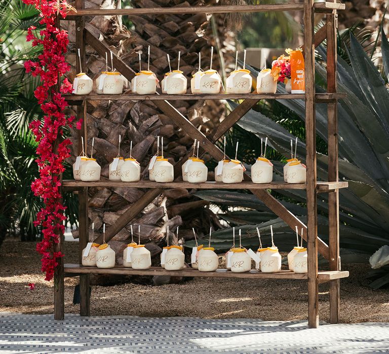 Personalised engraved coconuts on wooden shelves outdoors 