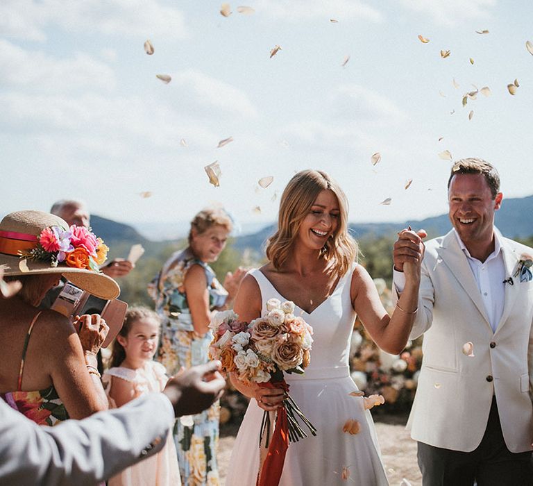 Bride & groom walk through petal confetti exit after outdoor Tuscan wedding ceremony 