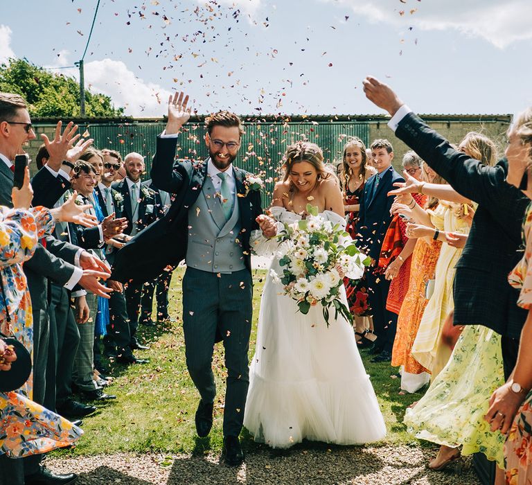 Hand-dried petal confetti is thrown over the bride and groom for their fun confetti exit after their non-denominational ceremony 